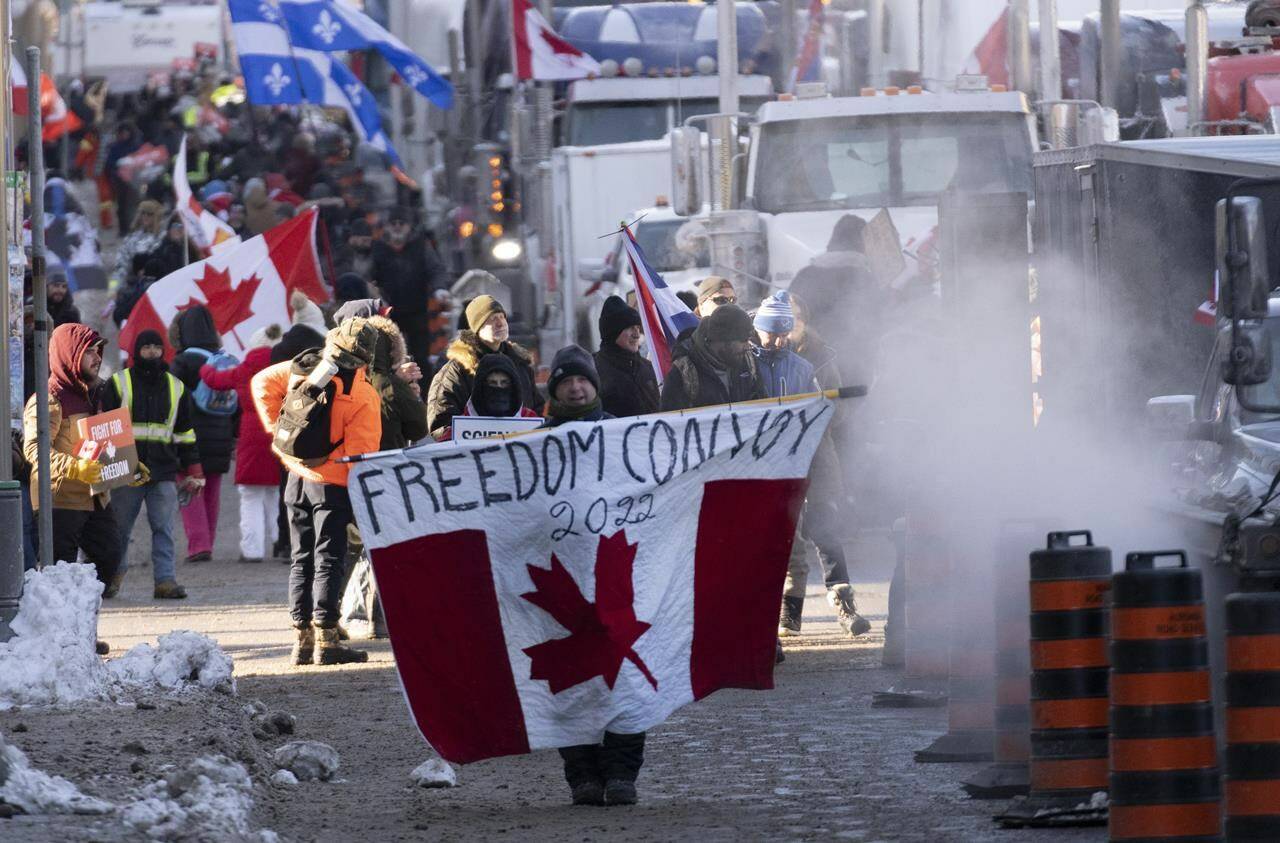 Protesters participating in a cross-country truck convoy protesting measures taken by authorities to curb the spread of COVID-19 and vaccine mandates walk near Parliament Hill in Ottawa on Saturday, Jan. 29, 2022. The “Freedom Convoy” protest against COVID-19 restrictions has been voted The Canadian Press news story of the year. THE CANADIAN PRESS/Adrian Wyld