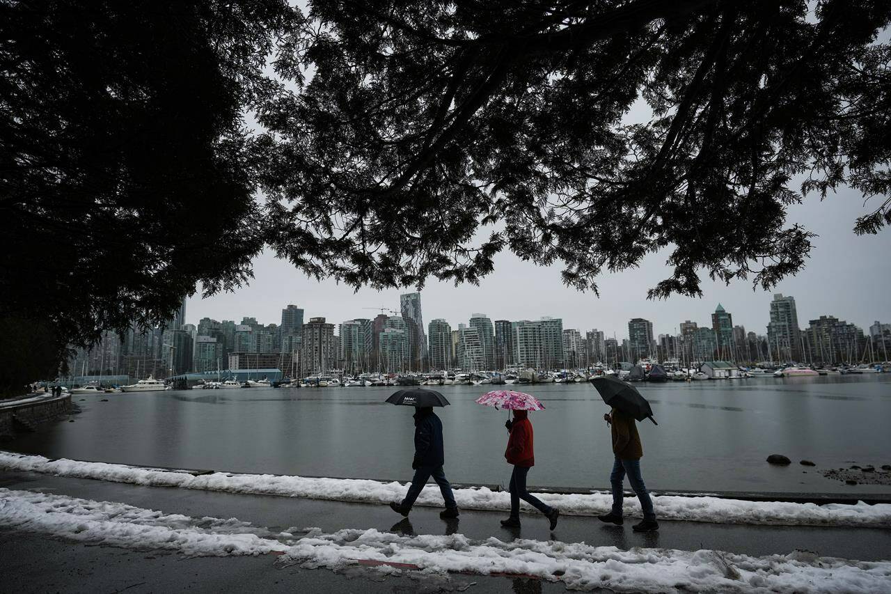 People walk along the Stanley Park seawall as rain falls Sunday, Dec. 25, 2022, while a small amount of snow remains after last week’s snowstorm in Vancouver. Flood watches and high streamflow advisories are posted across Vancouver Island and much of British Columbia’s inner south coast as heavy rain and high tides raise the risk of flooding after pre-Christmas snowstorms. THE CANADIAN PRESS/Darryl Dyck