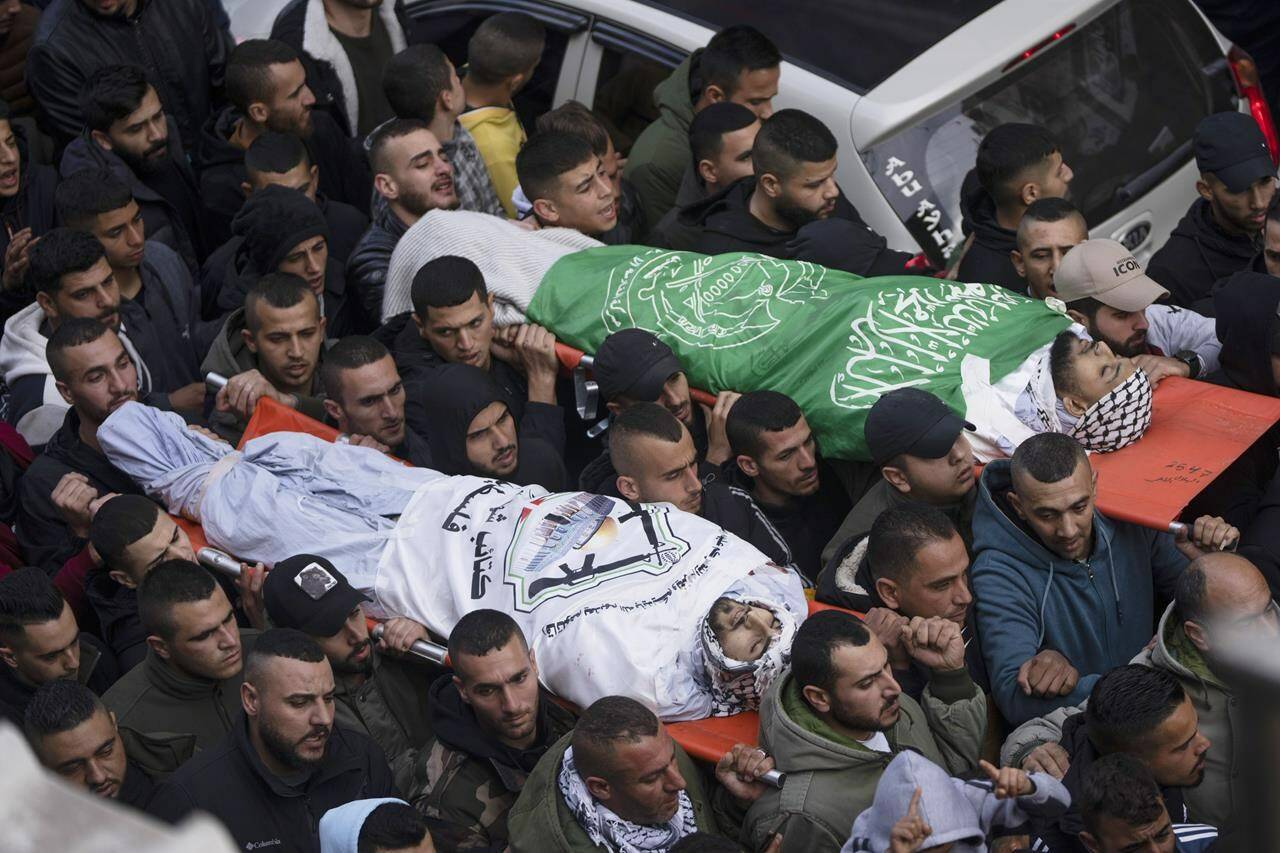 Mourners carry the bodies of Samer Houshiyeh, 21, left, and Fouad Abed, 25, during their funeral in the West Bank city of Jenin, Monday, Jan. 2, 2023. The two men were killed in the village of Kafr Dan near the northern city of Jenin. The Israeli military said it entered Kafr Dan late Sunday to demolish the houses of two Palestinian gunmen who killed an Israeli soldier during a firefight in September. The military said troops came under heavy fire and fired back at the shooters. (AP Photo/Nasser Nasser)
