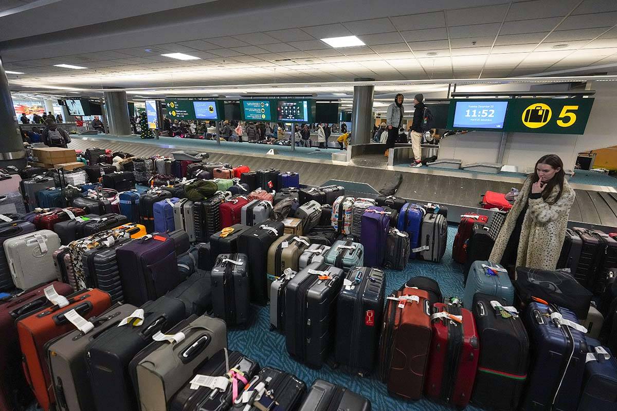 A woman searches for her luggage at Vancouver International Airport after a snowstorm crippled operations leading to cancellations and major delays on Dec. 20, 2022. Two weeks later, the airport says it’s still working to reunite hundreds of pieces of luggage with travellers. (Darryl Dyck/The Canadian Press via AP)