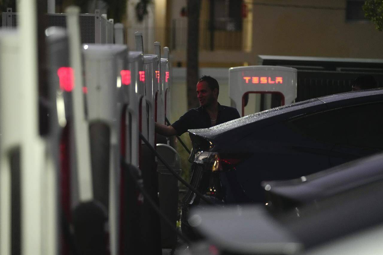 FILE - A driver charges his car at a Tesla Supercharger station, Wednesday, Nov. 16, 2022, in Miami. A tweet from Elon Musk indicating that Tesla might allow some owners who are testing a “Full Self-Driving” system to disable an alert that reminds them to keep their hands on the steering wheel has drawn attention from U.S. safety regulators. (AP Photo/Rebecca Blackwell, File)