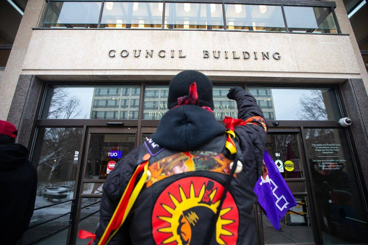 A member of the First Nations Indigenous Warriors raises his fist toward the doors at Winnipeg City Hall, Thursday, Dec. 15, 2022. A leading human rights group says Canada is failing to address long-standing abuses, delivering a scathing rebuke of what it calls the federal government’s inadequate climate policy and violations of the rights of Indigenous people and immigration detainees. THE CANADIAN PRESS/Daniel Crump