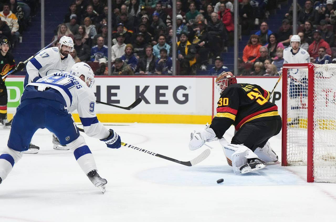 Tampa Bay Lightning’s Steven Stamkos, left, scores against Vancouver Canucks goalie Spencer Martin, to record his 500th career goal during first period NHL hockey action in Vancouver on Wednesday, January 18, 2023. THE CANADIAN PRESS/Darryl Dyck