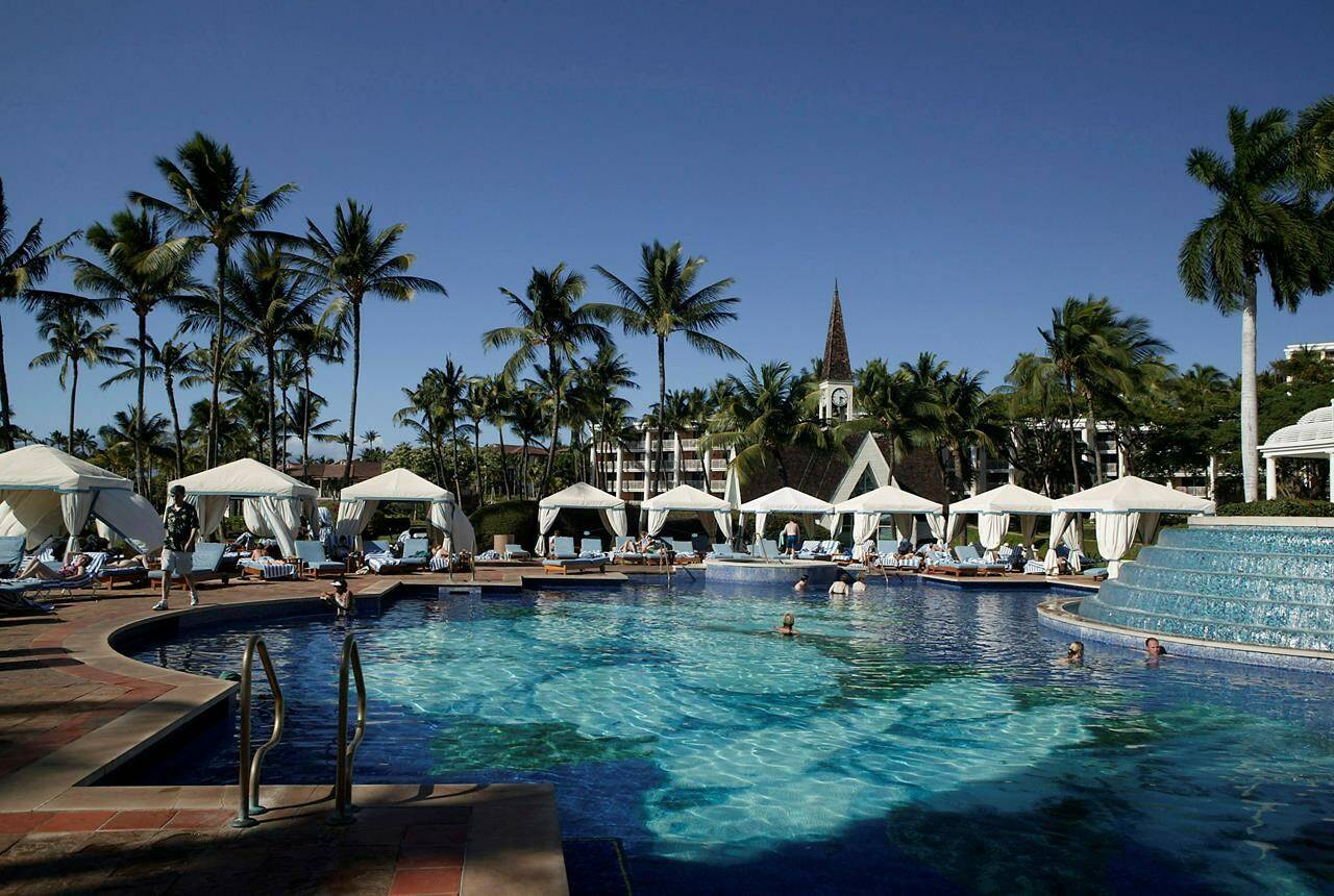 Guests are are shown in one of the many pools at the Grand Wailea Resort, Feb. 6, 2006 in Wailea, Maui, Hawaii. Resort fees that aren’t advertised as part of the room rate of a hotel stay can surprise many travelers when they see the final price. Some hotels say the separate fees help cover the costs of valuable amenities like classes or equipment rentals. Those fees may even encourage guests to use these amenities. But the government says resort fees are a play for profit because they reduce the commissions resorts must pay travel agents based on nightly rates and resorts aren’t being transparent enough about the added fees when travelers are trying to book. (AP Photo/Marco Garcia, file)