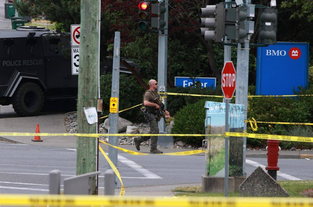 Police respond to gunfire at the Bank of Montreal in Saanich, B.C., on Tuesday, June 28, 2022. Police will release the results of their investigation into the dramatic shootout in which two gunmen were killed outside the bank. THE CANADIAN PRESS/Chad Hipolito