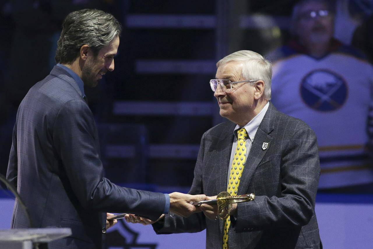 Former Buffalo Sabres goaltender Ryan Miller accepts a saber from Terry Pegula, owner of Pegula Sports and Entertainment, as Miller was honored before the Sabres’ NHL hockey game against the New York Islanders on Thursday, Jan. 19, 2023, in Buffalo, N.Y. (AP Photo/Joshua Bessex)