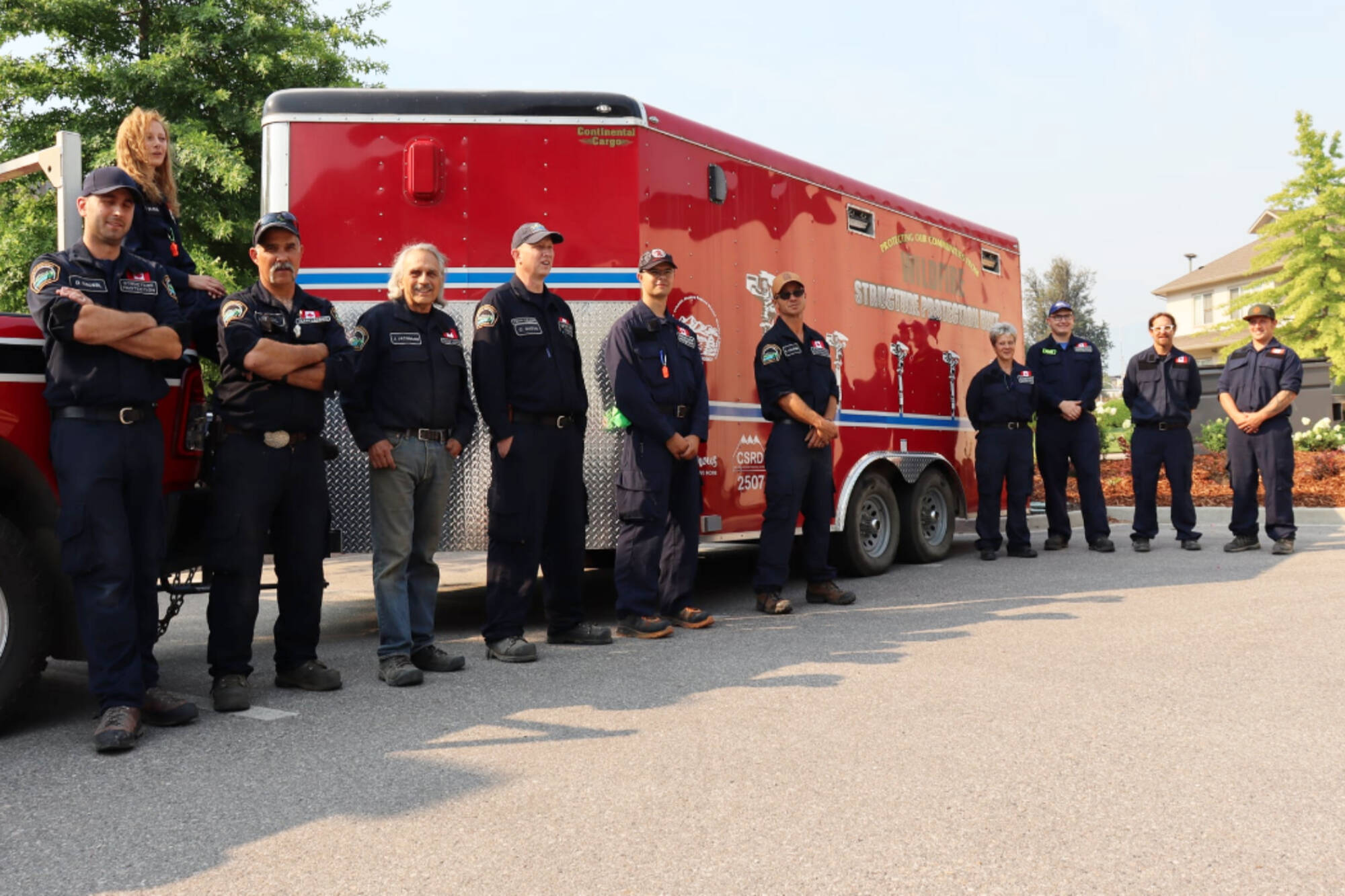 Two Columbia Shuswap Regional District fire crews stand next to a structure protection unit for a photograph before being deployed to fight wildfires in July 2021. (CSRD photo)