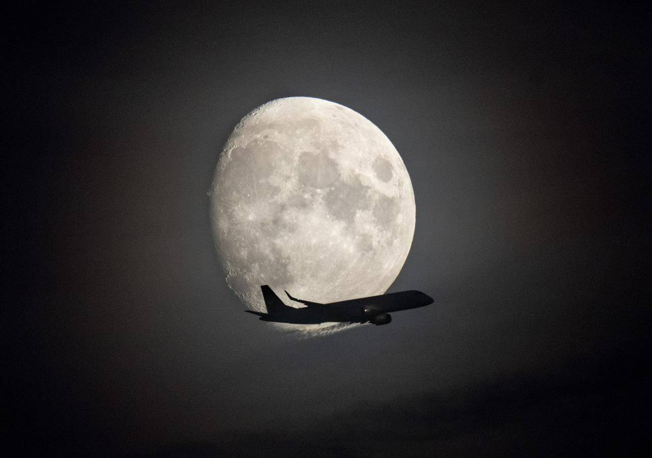 An aircraft is silhouetted against the moon in Frankfurt, Germany, Thursday, Oct. 6, 2022. The number of commercial pilot licences issued in Canada annually has declined by more than 80 per cent since 2019, even as aviation experts warn of an ever-growing labour shortage that threatens to disrupt Canada’s airline industry. THE CANADIAN PRESS/AP/Michael Probst