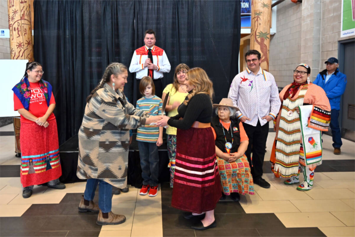 Kristine Jack, left, hands over the eagle feather and metaphorical reins of the Pow Wow Between the Lakes to Haley Regan. The Pow Wow will be held at the South Okanagan Events Centre for the first time in 2023. (Brennan Phillips - Penticton Western News)