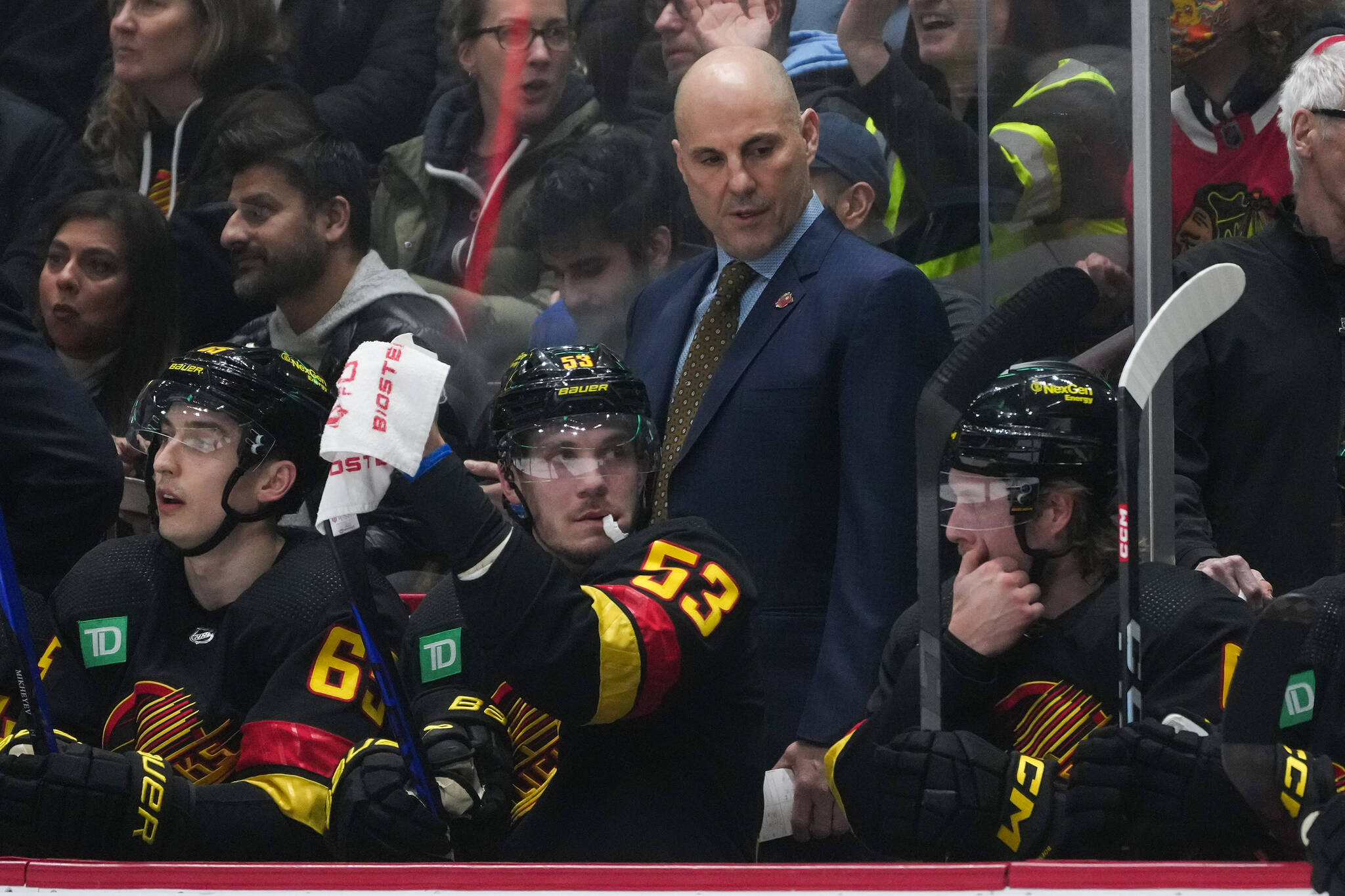 Vancouver Canucks head coach Rick Tocchet, back, stands behind Ilya Mikheyev, from left to right, Bo Horvat and Brock Boeser during the first period of an NHL hockey game against the Chicago Blackhawks in Vancouver, on Tuesday, January 24, 2023. THE CANADIAN PRESS/Darryl Dyck