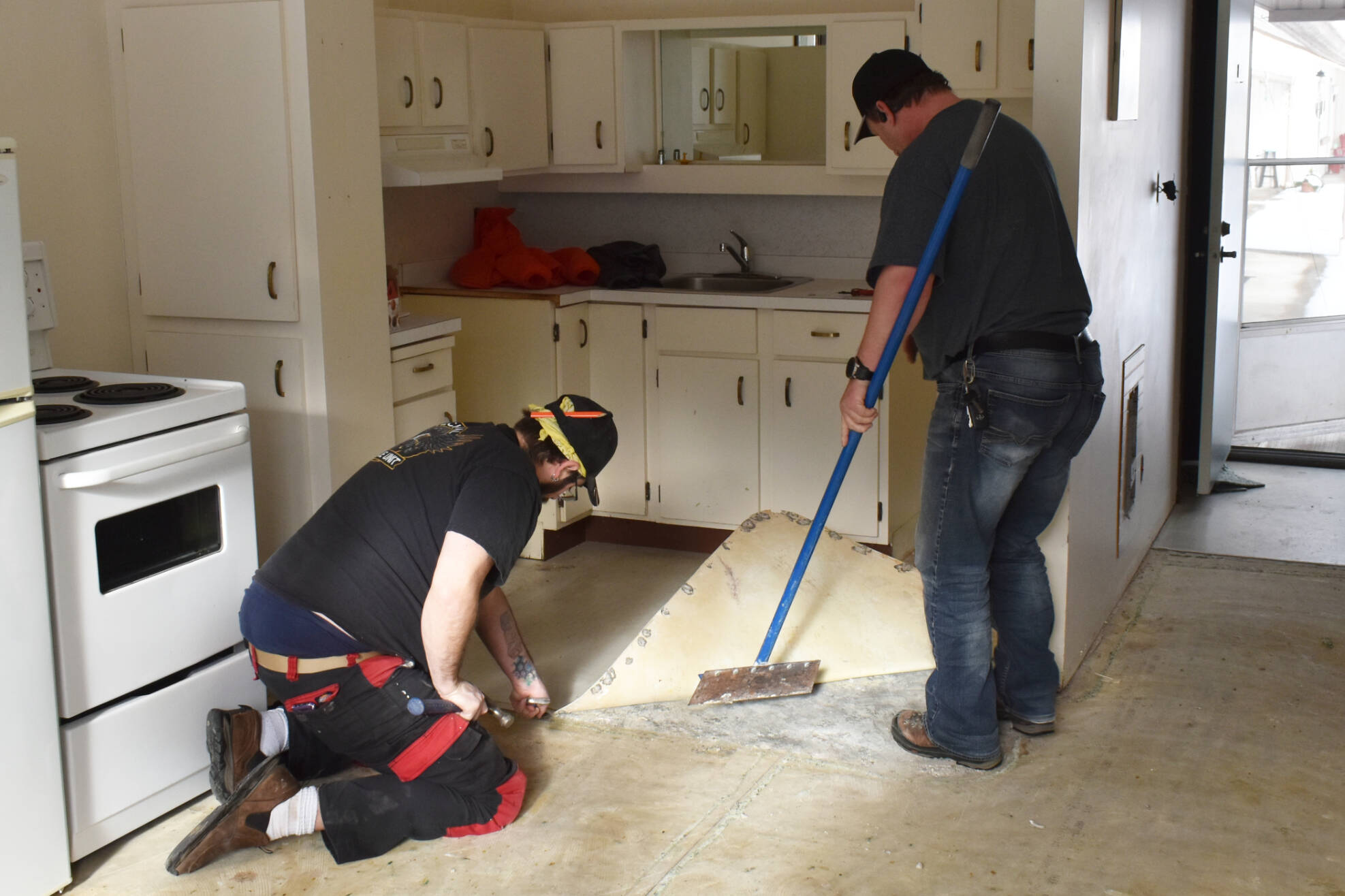 Jeff VanDooyeweert and Chris Wilson pull up laminate flooring in the kitchen of a unit at The Haven seniors’ living complex in Sicamous as it undergoes a renovation Saturday, Feb. 4, 2023. (Rebecca Willson- Eagle Valley News)