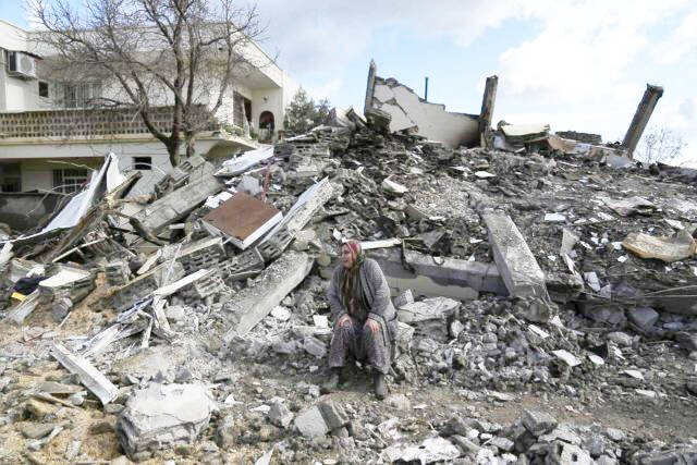 A woman sits on the rubble as emergency rescue teams search for people under the remains of destroyed buildings in Nurdagi town on the outskirts of Osmaniye city southern Turkey, Tuesday, Feb. 7, 2023. Ottawa says Canada will contribute $10 million to earthquake relief efforts in Turkey and Syria as part of an initial aid package. (Photo by Khalil Hamra, the Canadian Press/Ap)