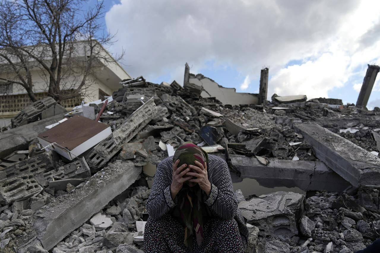 A woman sits on the rubble as emergency rescue teams search for people under the remains of destroyed buildings in Nurdagi town on the outskirts of Osmaniye city southern Turkey, Tuesday, Feb. 7, 2023. The earthquake that ravaged Turkey and Syria this week offers both lessons and warnings for people in British Columbia as images emerge of the human devastation and costly damage, Canadian seismology experts say. THE CANADIAN PRESS/AP, Khalil Hamra
