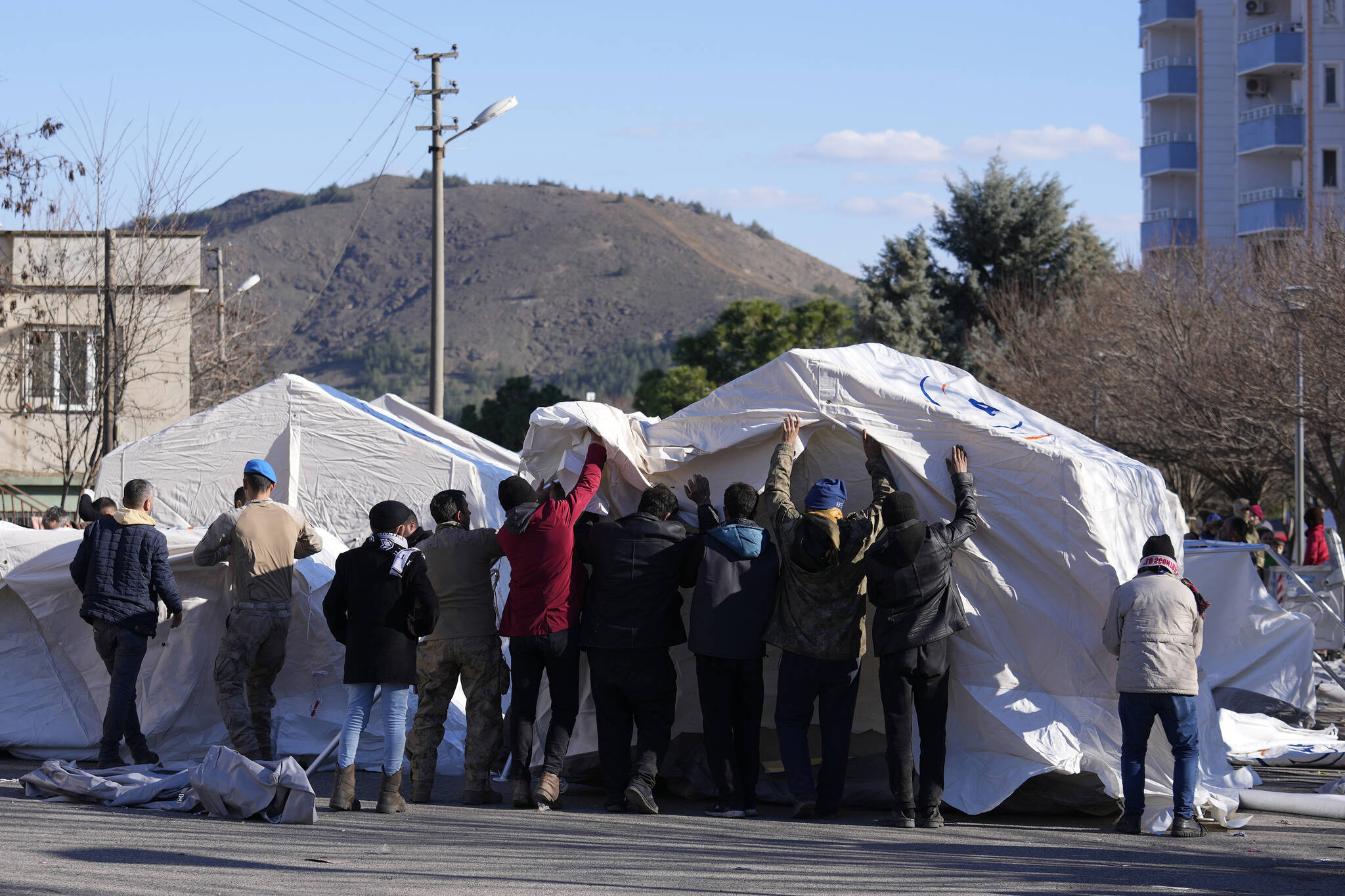 Soldiers and local residents are set up a tent, in Aslanli, southeastern Turkey, Thursday, Feb. 9, 2023. Tens of thousands of people who lost their homes in a catastrophic earthquake huddled around campfires in the bitter cold and clamored for food and water Thursday, three days after the temblor hit Turkey and Syria. (AP Photo/Kamran Jebreili)