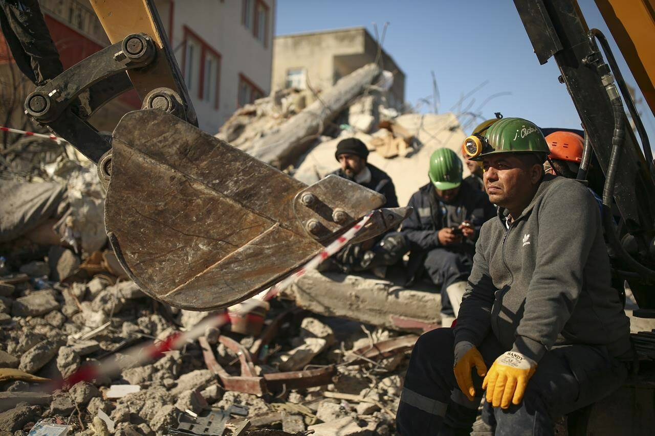 Turkish rescue workers stand by a collapsed building in Adiyaman, southern Turkey, Saturday, Feb. 11, 2023. Rescuers in Turkey miraculously continued to pull earthquake survivors out of the rubble on Saturday. The unlikely rescues, coming over four days after Monday’s 7.8-magnitude quake brought down thousands of buildings in Turkey and Syria, offered fleeting moments of joy amid a catastrophe that has killed nearly 24,000 people, injured at least 80,000 others and left millions homeless.(AP Photo/Emrah Gurel)