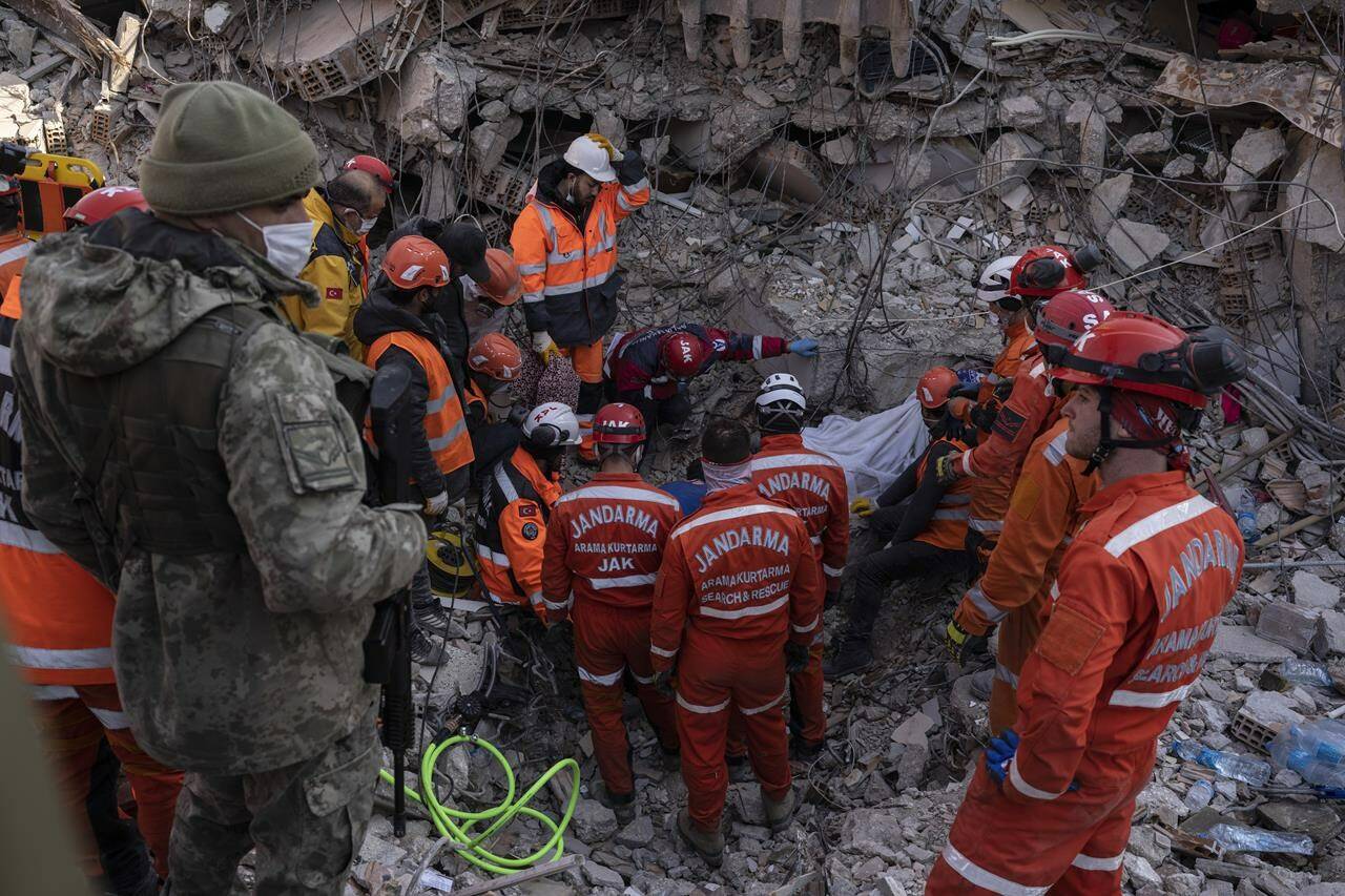 A Turkish soldier, left, watches as rescue workers of the search and rescue unit of the Turkish Gendarmerie General Command, JAK, work to pull 23-year-old Huseyin Seferoglou from the rubble of a collapsed building in Antakya, Turkey, on Sunday, Feb. 12, 2023. THE CANADIAN PRESS-AP-Petros Giannakouris