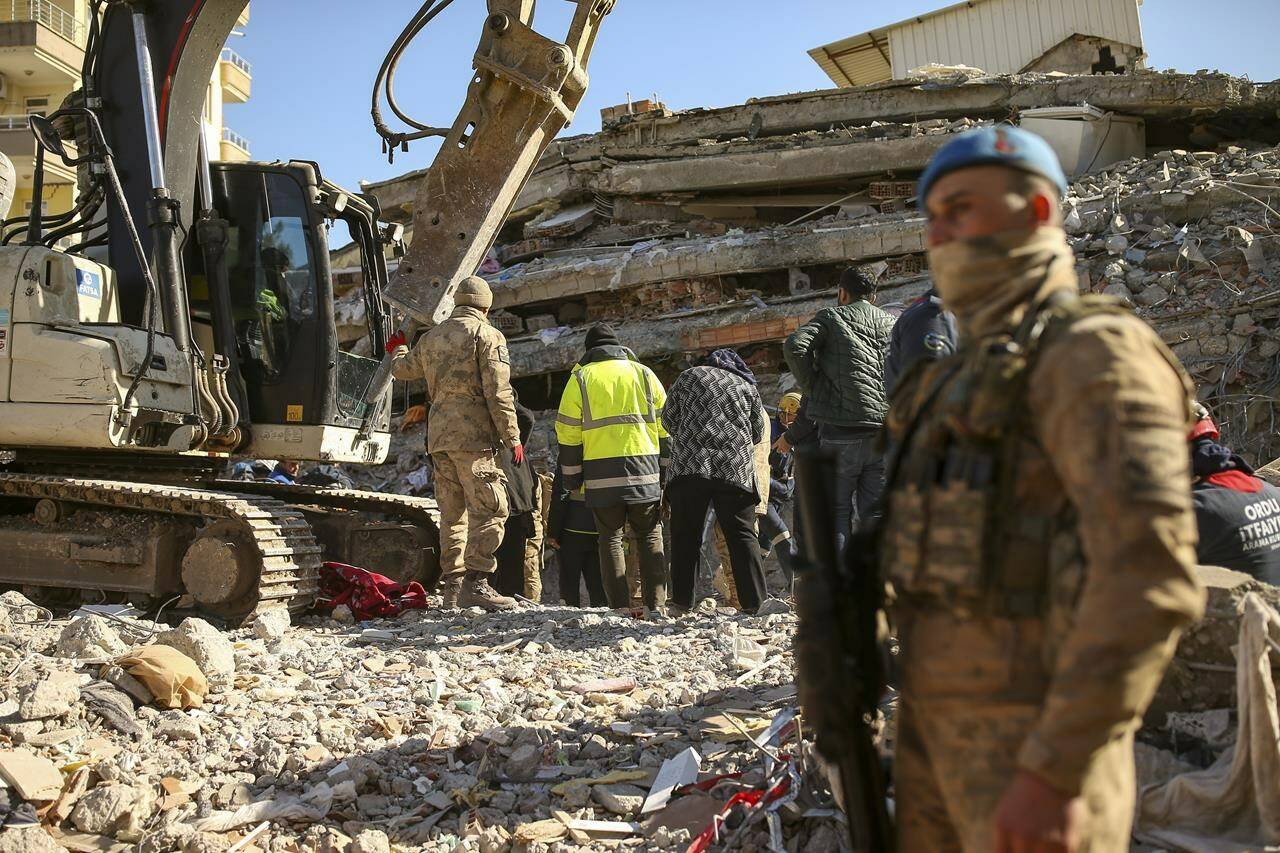 Rescue workers stand on a collapsed building in Adiyaman, southern Turkey, Monday, Feb. 13, 2023. The body of a young Canadian woman who was visiting Turkey has been found in the rubble of a building that collapsed during a massive earthquake on Feb. 6. THE CANADIAN PRESS/AP-Emrah Gurel