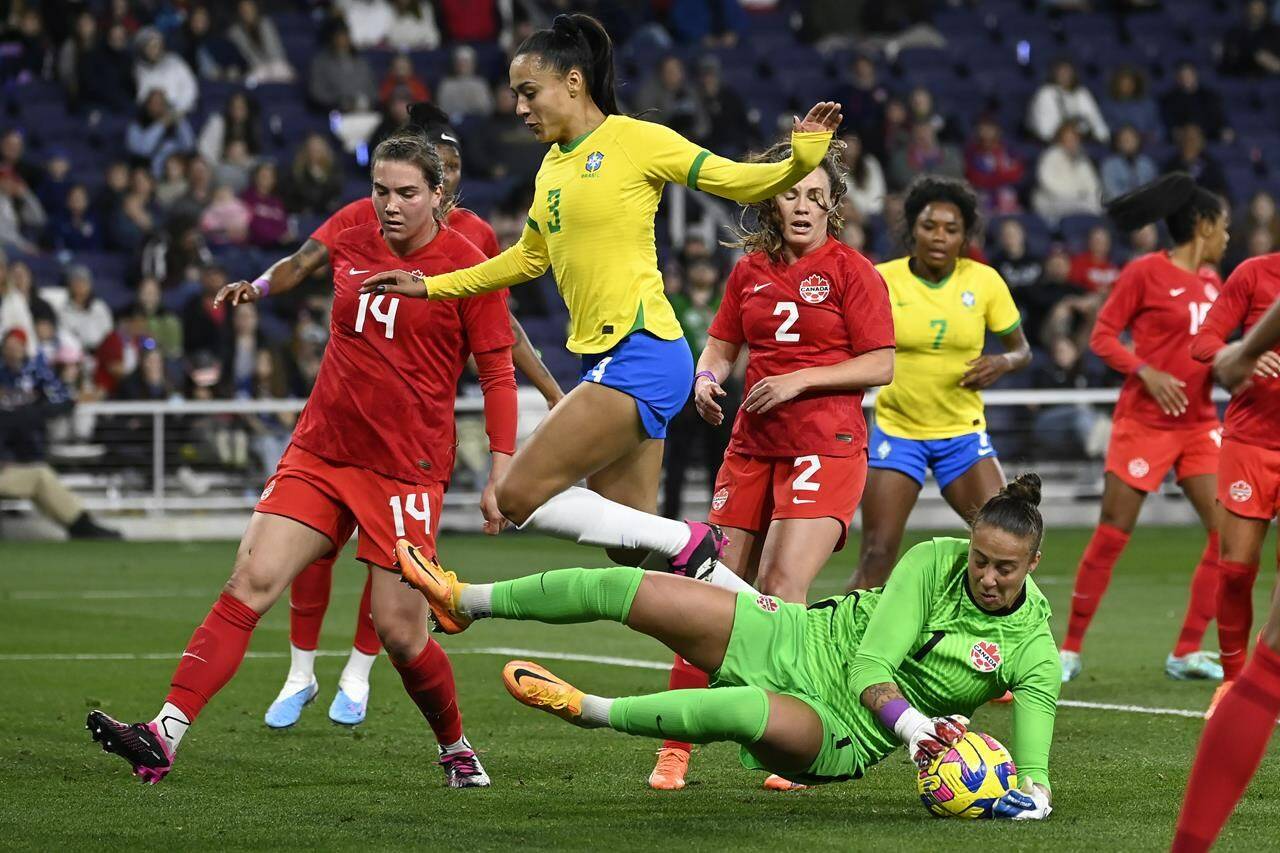 Canada goalkeeper Kailen Sheridan (1) grabs the ball as she stops a shot by Brazil during the first half of a SheBelieves Cup women’s soccer match Sunday, Feb. 19, 2023, in Nashville, Tenn. Brazil defender Kathellen (3) leaps over Sheridan. THE CANADIAN PRESS/AP-Mark Zaleski