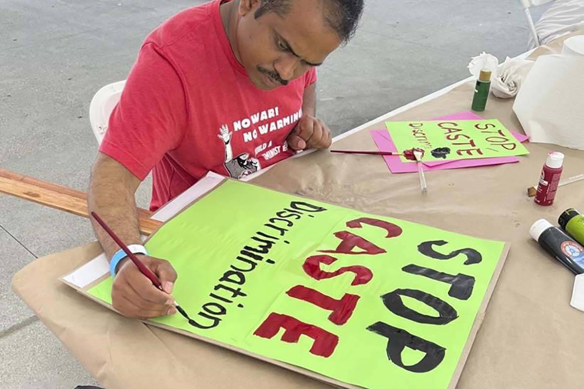 In this photo provided by Prem Pariyar, a Dalit Hindu from Nepal, he works on a banner at a People’s Summit for Democracy event in Los Angeles in June 2022. He moved to the U.S. in 2015, but says he couldn’t escape stereotyping and discrimination because of his caste-identifying last name, even as he tried to make a new life thousands of miles away from home. (Courtesy of Prem Pariyar)