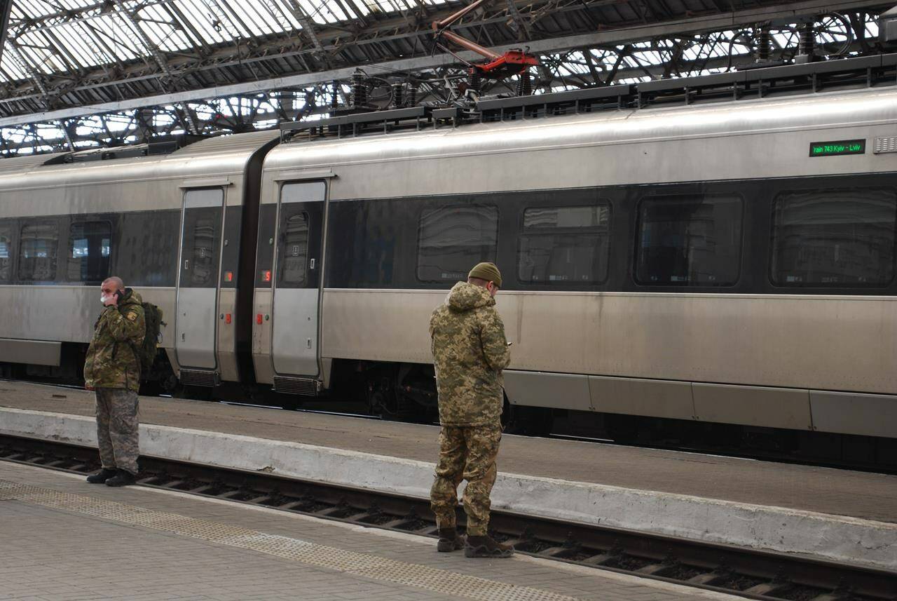 Passengers and military personnel wait on the platform of the Lviv train station in Western Ukraine on Feb. 18, 2023. Ukraine is appealing to Canada for rail parts and expertise to keep the embattled passenger and cargo rail system running as landmines and missile strikes threaten to stall the country's lifeline. THE CANADIAN PRESS/Laura Osman