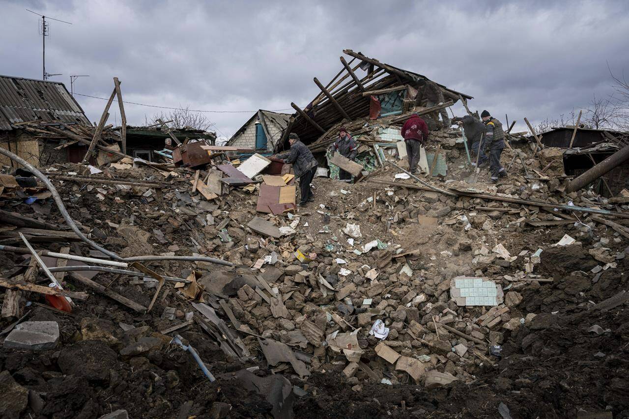 The residents of a house and their neighbours clear the rubble from a home that was destroyed by a Russian rocket in Maxymilianivka village, Ukraine, Tuesday, Feb. 21, 2023. Ukrainians woke up to their second year of war this morning, as the military continued to beat back invading Russian forces in the southeastern region of the country. THE CANADIAN PRESS/AP/Evgeniy Maloletka