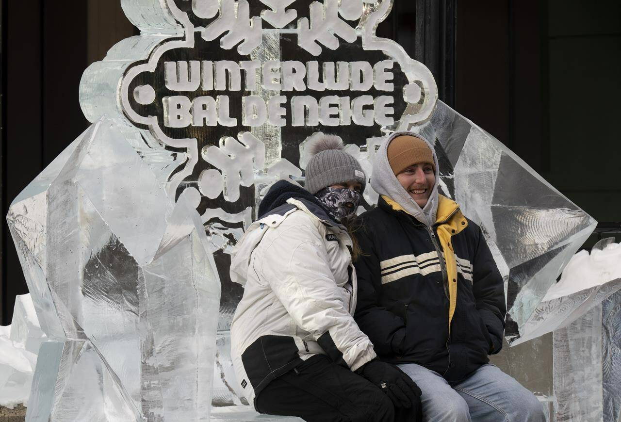 Two people sit on an ice-bench, part of an ice sculpture in downtown Ottawa, Friday, February 3, 2023. Mowafak Nema, second place winner of this year’s ice sculpting competition says weather like Ottawa has experienced this winter just means that sculptors have to adapt. THE CANADIAN PRESS/Adrian Wyld