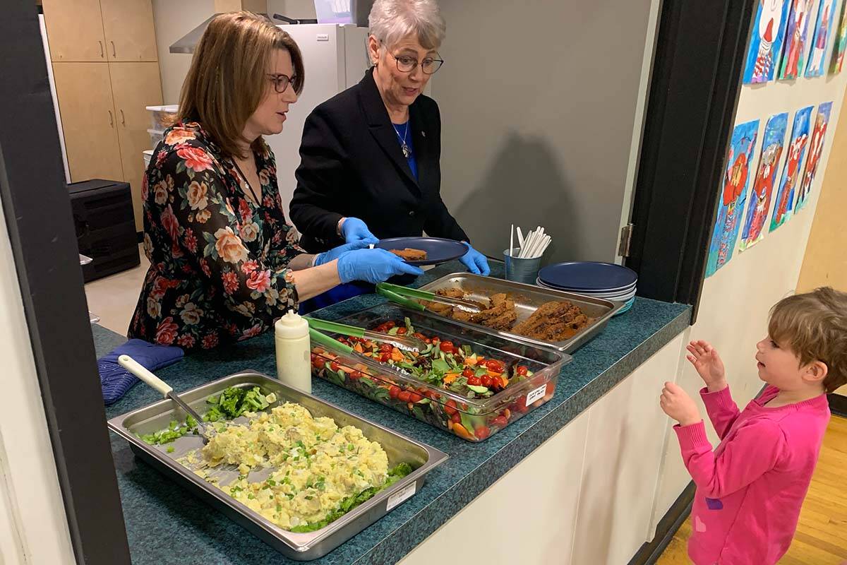 A Grade 1 student at Ruth King Elementary School in Langford, B.C., holds up her hands as principal Vicki Ives joined B.C.’s finance minister Katrine Conroy in serving up lunch Monday (Feb. 27). Conroy will present the provincial budget tomorrow. (Wolf Depner/News Staff)