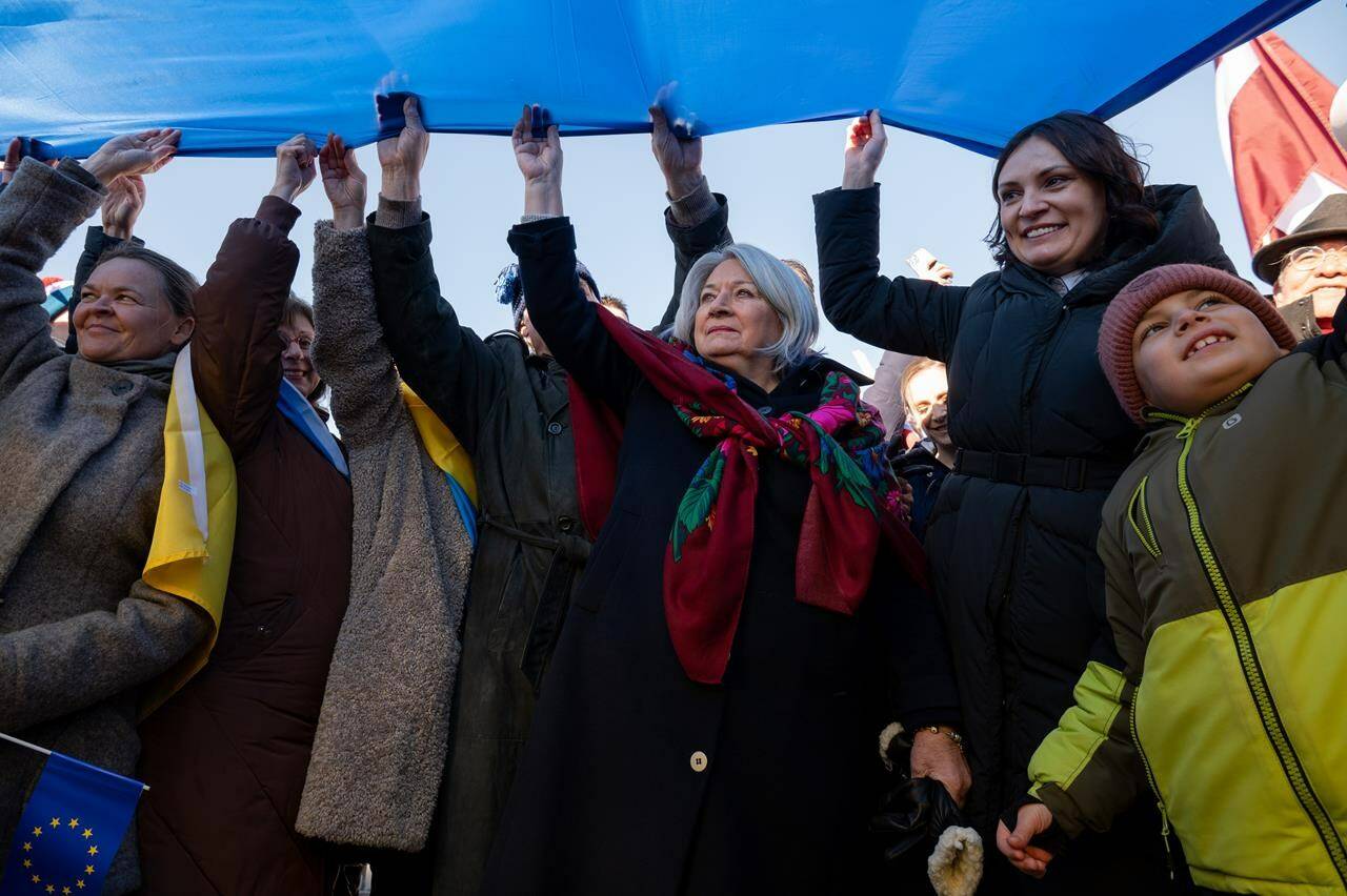 Governor General Mary Simon and Yuliya Kovaliv, Ambassador of Ukraine to Canada, right, hold a section of the Ukrainian flag during the ‘Stand in Solidarity with Ukraine’ event marking the one-year anniversary of the Russian invasion of Ukraine at the Flora Footbridge in Ottawa, on Monday, Feb. 20, 2023. THE CANADIAN PRESS/Spencer Colby