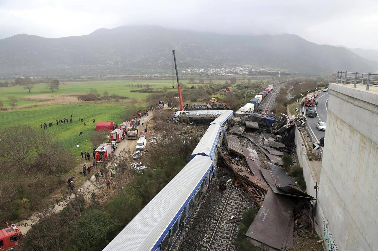 A crane operator, firefighters and rescuers work the scene of a collision in Tempe, about 376 kilometers (235 miles) north of Athens, near Larissa city, Greece, Wednesday, March 1, 2023. A train carrying hundreds of passengers has collided with an oncoming freight train in northern Greece, killing and injuring dozens passengers. (AP Photo/Vaggelis Kousioras)