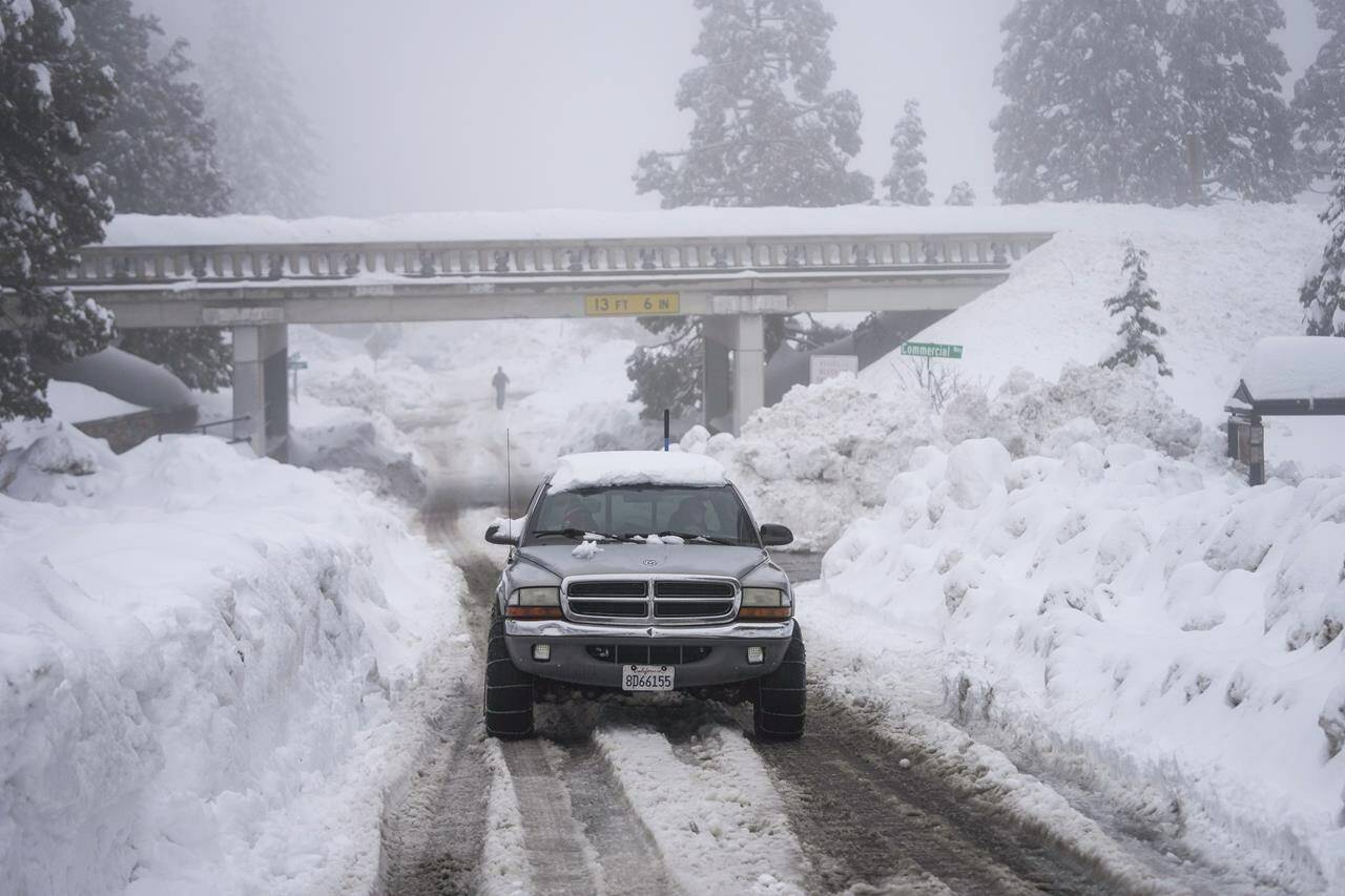 A truck drives along snow berms in Running Springs, Calif., Tuesday, Feb. 28, 2023. Beleaguered Californians got hit again Tuesday as a new winter storm moved into the already drenched and snow-plastered state, with blizzard warnings blanketing the Sierra Nevada and forecasters warning residents that any travel was dangerous. (AP Photo/Jae C. Hong)
