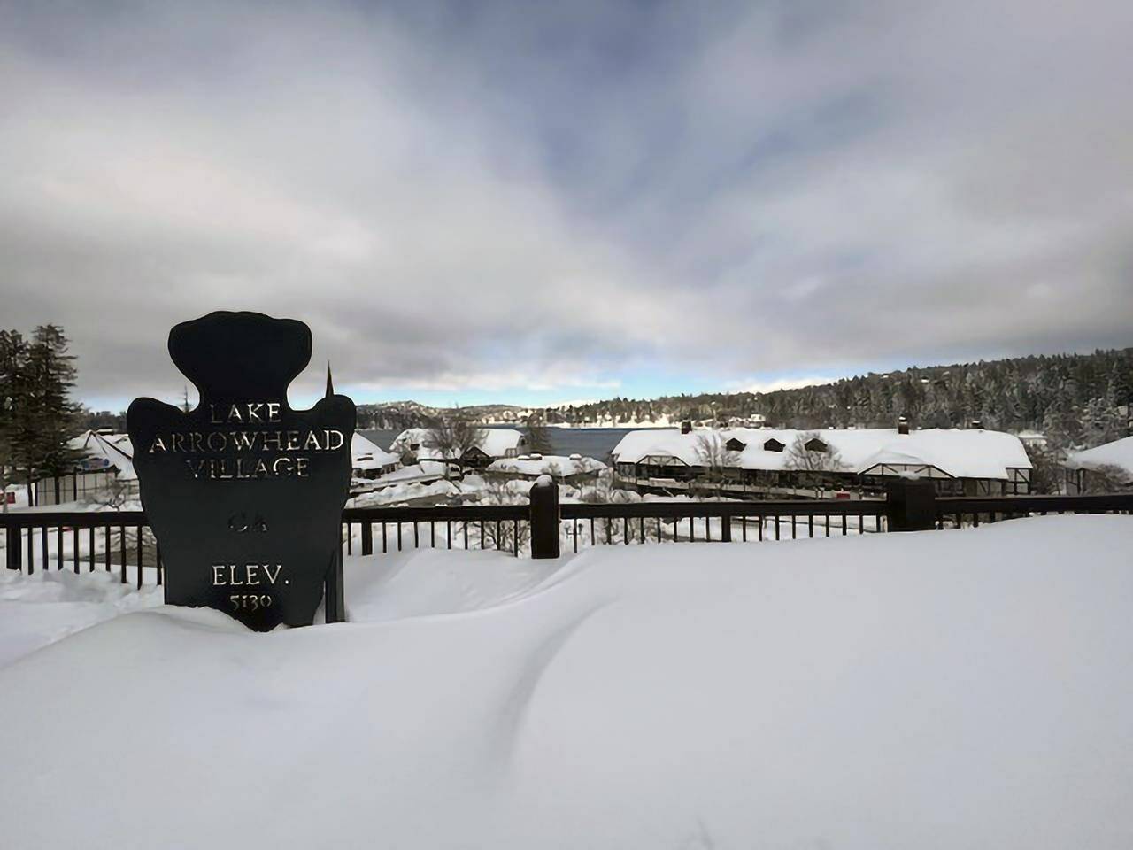 A sign for Lake Arrowhead Village is seen covered in snow on Sunday, Feb. 26, 2023 in the San Bernardino Mountains of San Bernardino County, Calif. Beleaguered Californians got hit again Tuesday as a new winter storm moved into the already drenched and snow-plastered state, with blizzard warnings blanketing the Sierra Nevada and forecasters warning residents that any travel was dangerous. (Matthew Cobb via AP)
