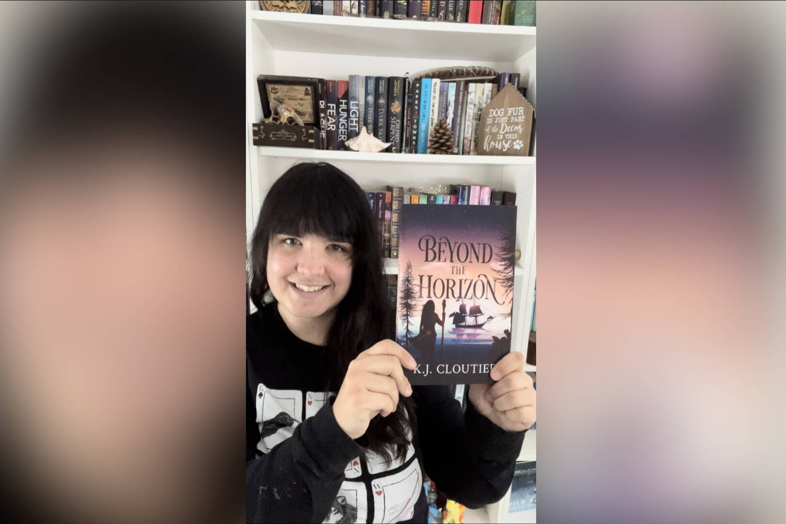 K.J. Cloutier holds up a copy of her book Beyond the Horizon, published on Feb. 7 2023, which she has been working on in some iteration since she was 14 years old. (Contributed)