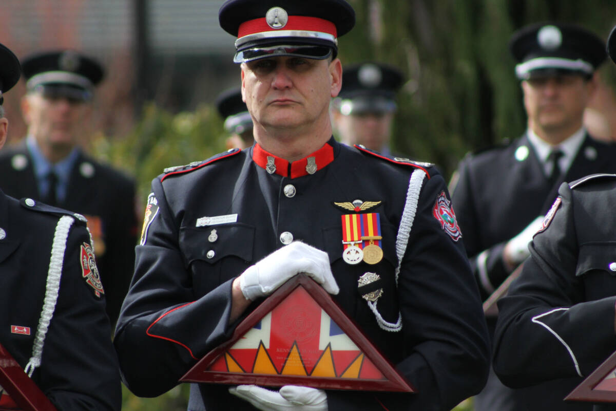 Oak Bay Fire Lt. Jason Joynson holds the flag of fallen colleague chaplain Kenneth Gill, who died of cancer in 2018, at the south lawn of the legislature in Victoria Monday (March 6). (Austin Westphal/News Staff)