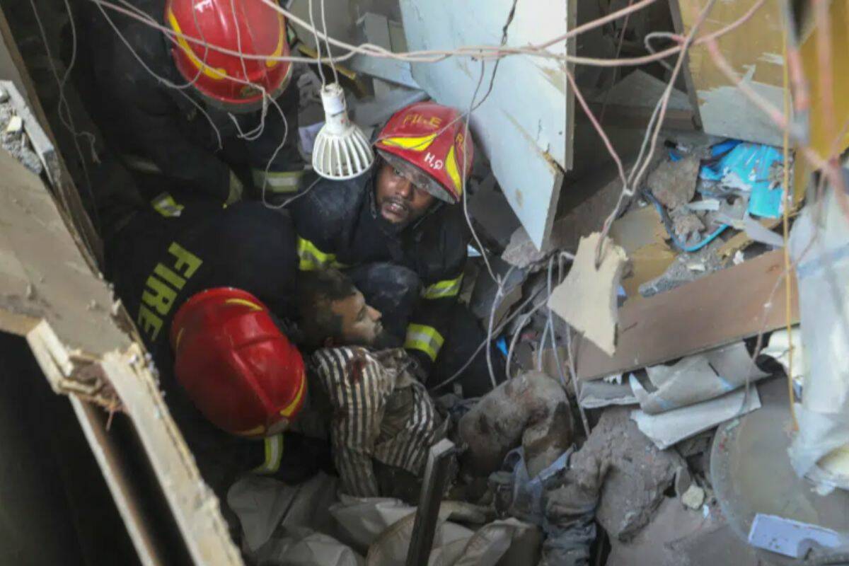Fire officials rescue an injured person from the debris of a commercial building after an explosion, in Dhaka, Bangladesh, Tuesday, March 7, 2023. An explosion in a seven-story commercial building in Bangladesh's capital has killed at least 14 people and injured dozens. Officials say the explosion occurred in a busy commercial area of Dhaka. (AP Photo/Abdul Goni)