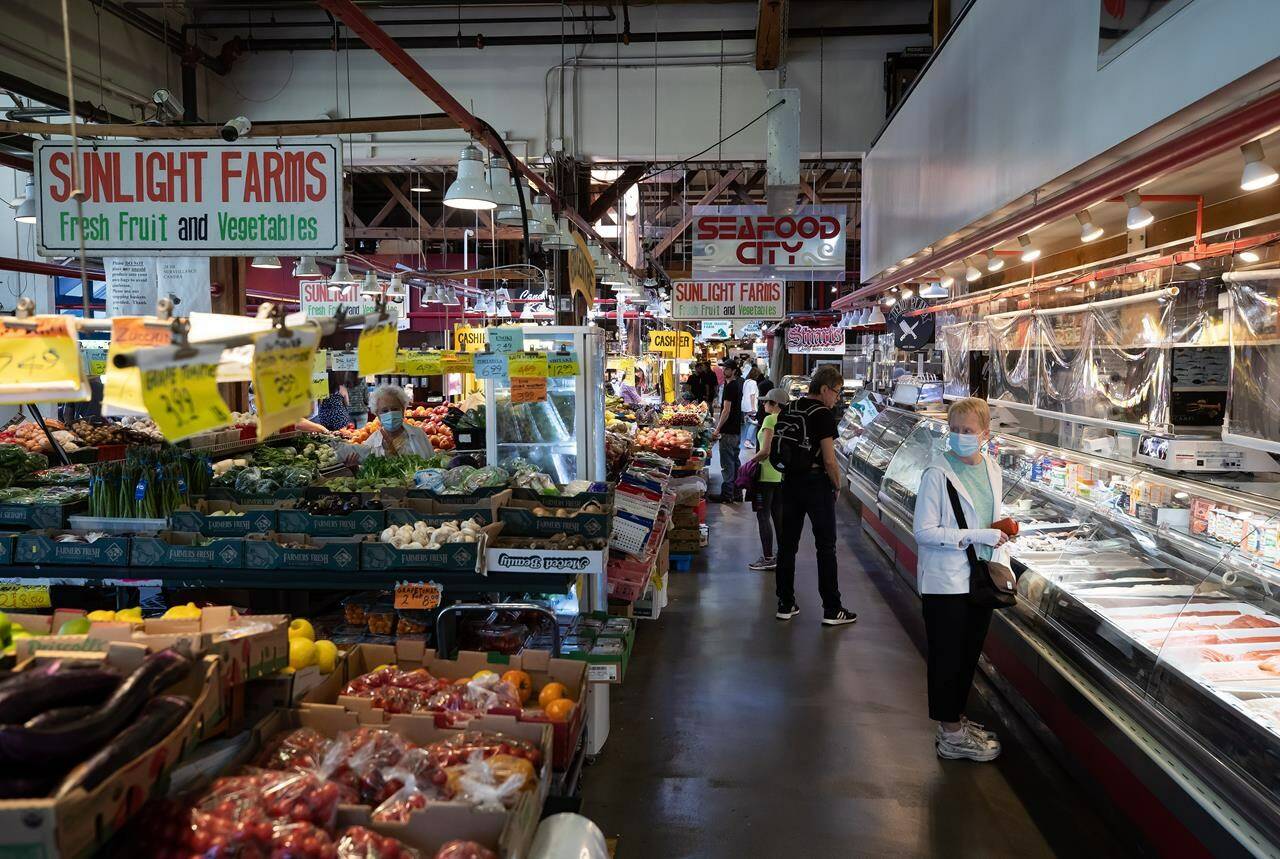 People shop for produce and seafood in Vancouver, on Wednesday, July 20, 2022. A new report by RBC says Canadians are on average making fewer grocery store runs as food inflation persists, but still spending roughly the same amount per trip. THE CANADIAN PRESS/Darryl Dyck