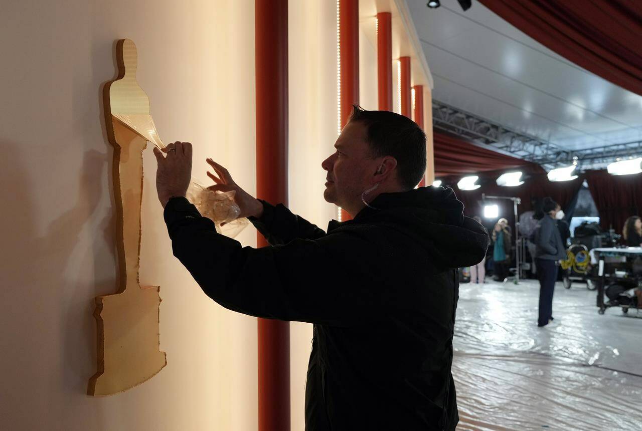 Art director Jerry Sonnenberg peels protective plastic off an Oscar decoration In preparation for Sunday’s 95th Academy Awards, Friday, March 10, 2023, outside the Dolby Theatre in Los Angeles. (AP Photo/Chris Pizzello)