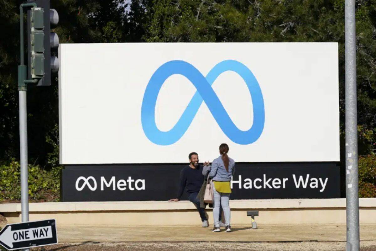 People talk near a Meta sign outside of the company's headquarters in Menlo Park, Calif., Tuesday, March 7, 2023. Facebook’s parent Meta will slash another 10,000 jobs and will not fill 5,000 open positions as the social media pioneer cuts costs. (AP Photo/Jeff Chiu)