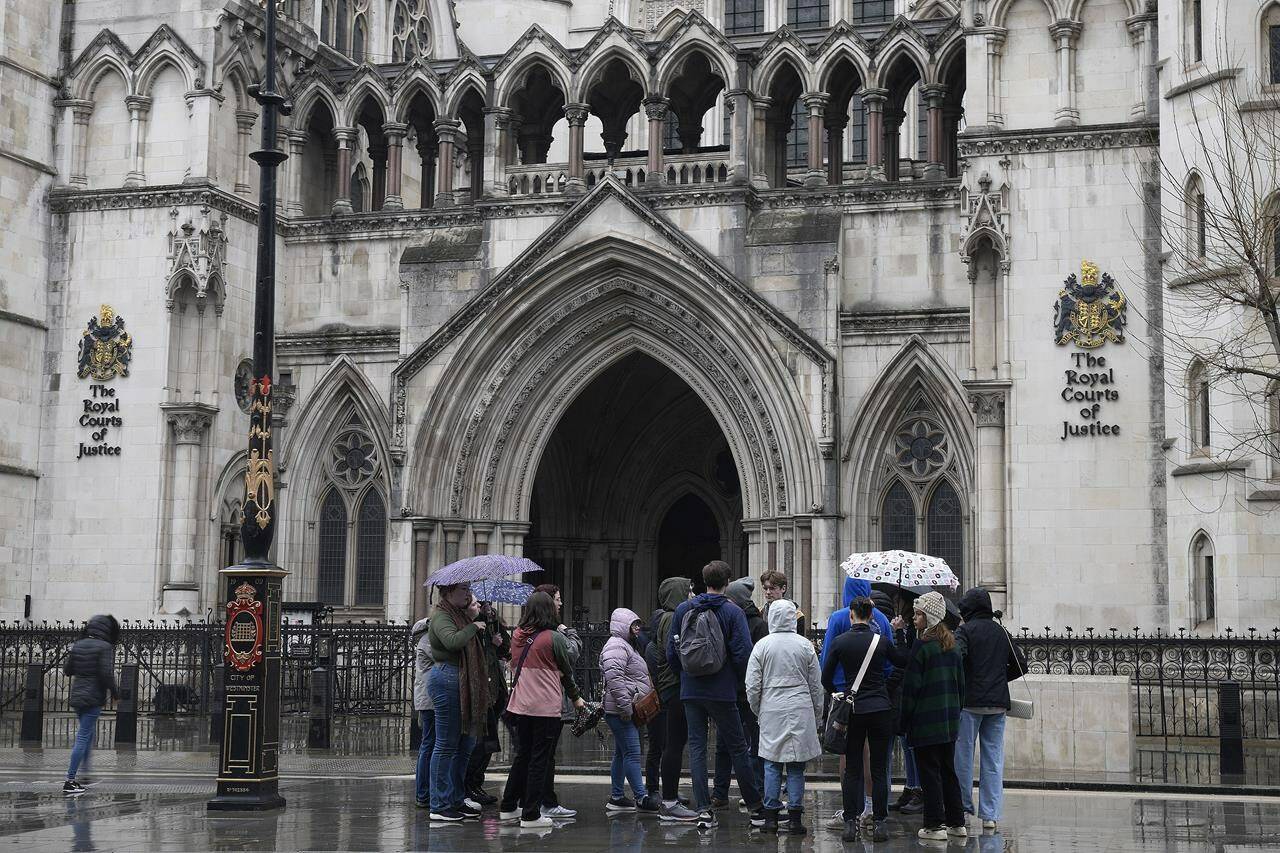 People stand outside the Royal Court of Justice in London, Friday, March 17, 2023. The Duke of Sussex, Prince Harry is suing Associated Newspapers Limited (ANL) over an article about his separate judicial review proceedings against the Home Office regarding security arrangements for himself and his family when they are in the UK. (AP Photo/Frank Augstein)