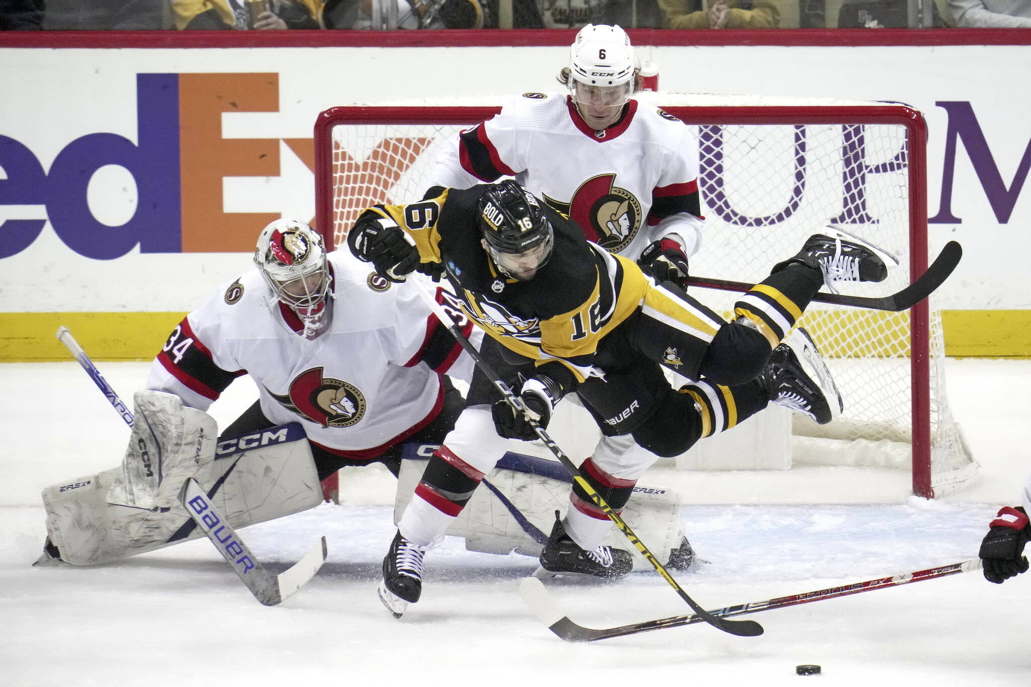 Pittsburgh Penguins’ Jason Zucker (16) is checked to the ice by Ottawa Senators’ Jakob Chychrun (6) in front of goaltender Dylan Ferguson (34) during the first period of an NHL hockey game in Pittsburgh, Monday, March 20, 2023. (AP Photo/Gene J. Puskar)